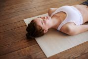 Frau liegt mit geschlossenen Augen auf Yogamatte Frau liegt mit geschlossenen Augen auf Yogamatte